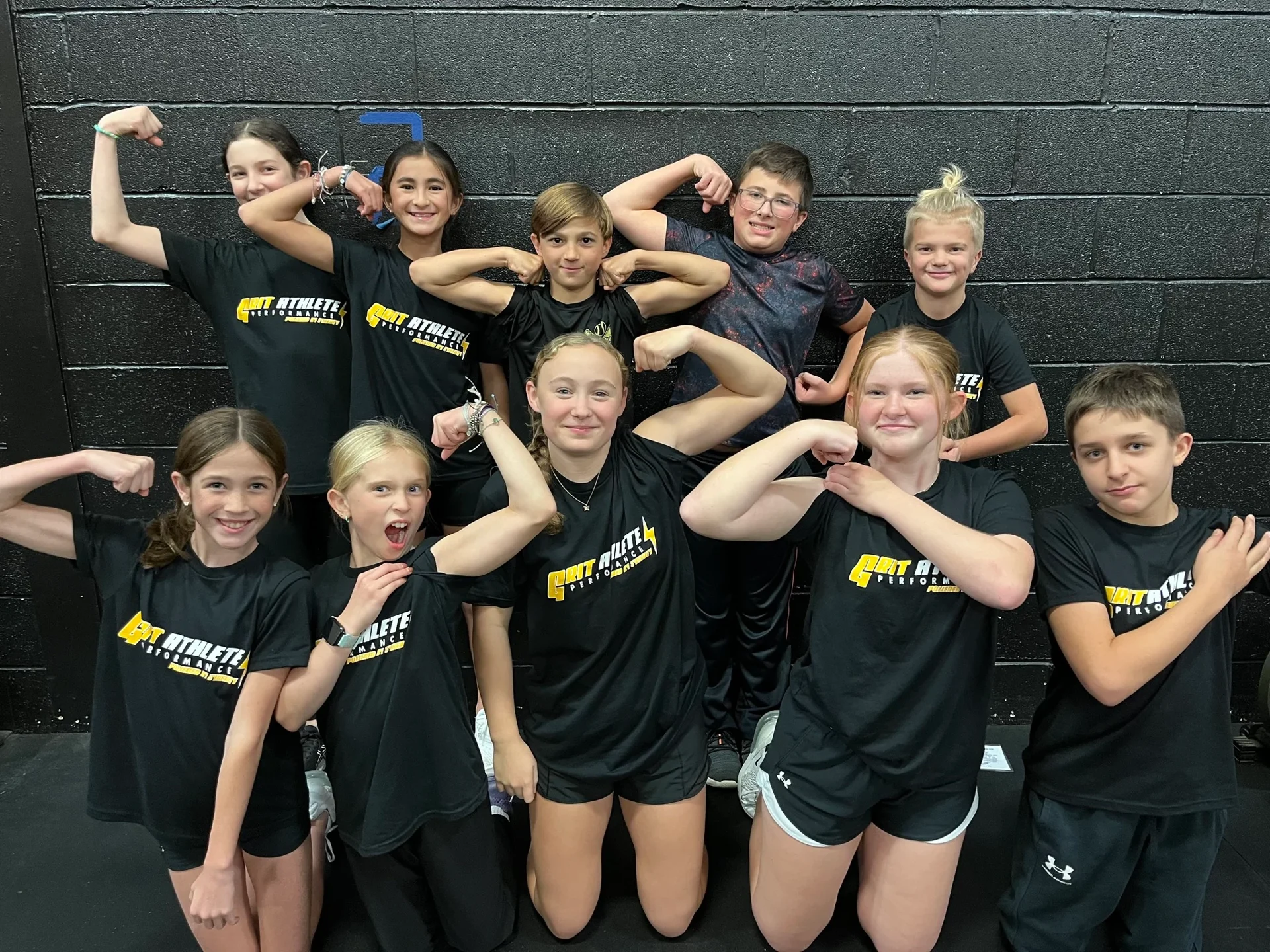 Group of young GRIT athletes flexing in the Synergy gym