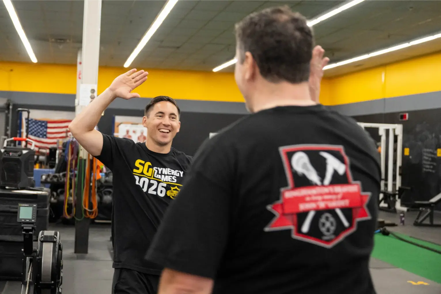 A Synergy Athletics coach high-fiving a member in the gym