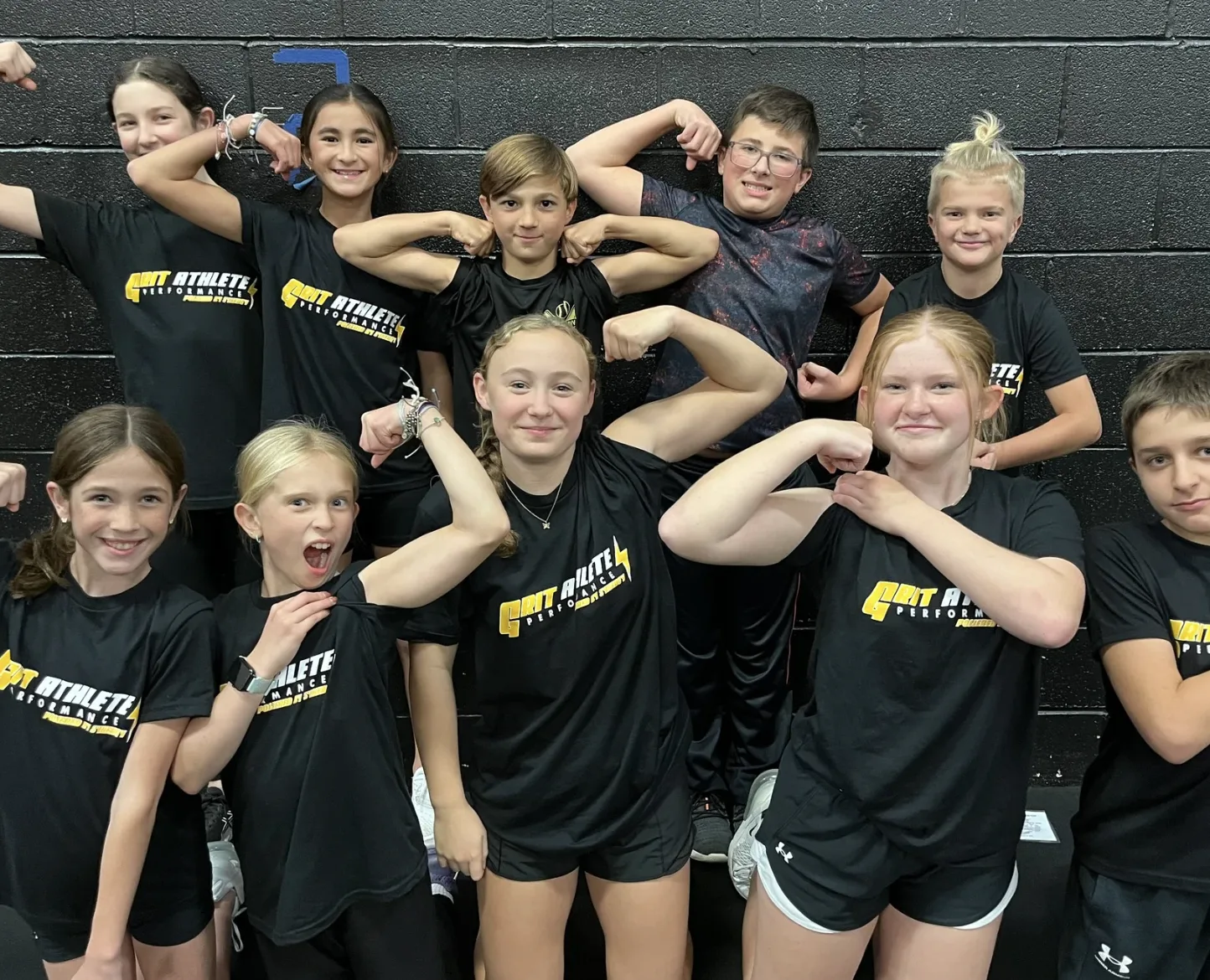 Young GRIT athletes flexing in their GRIT Athlete Performance shirts