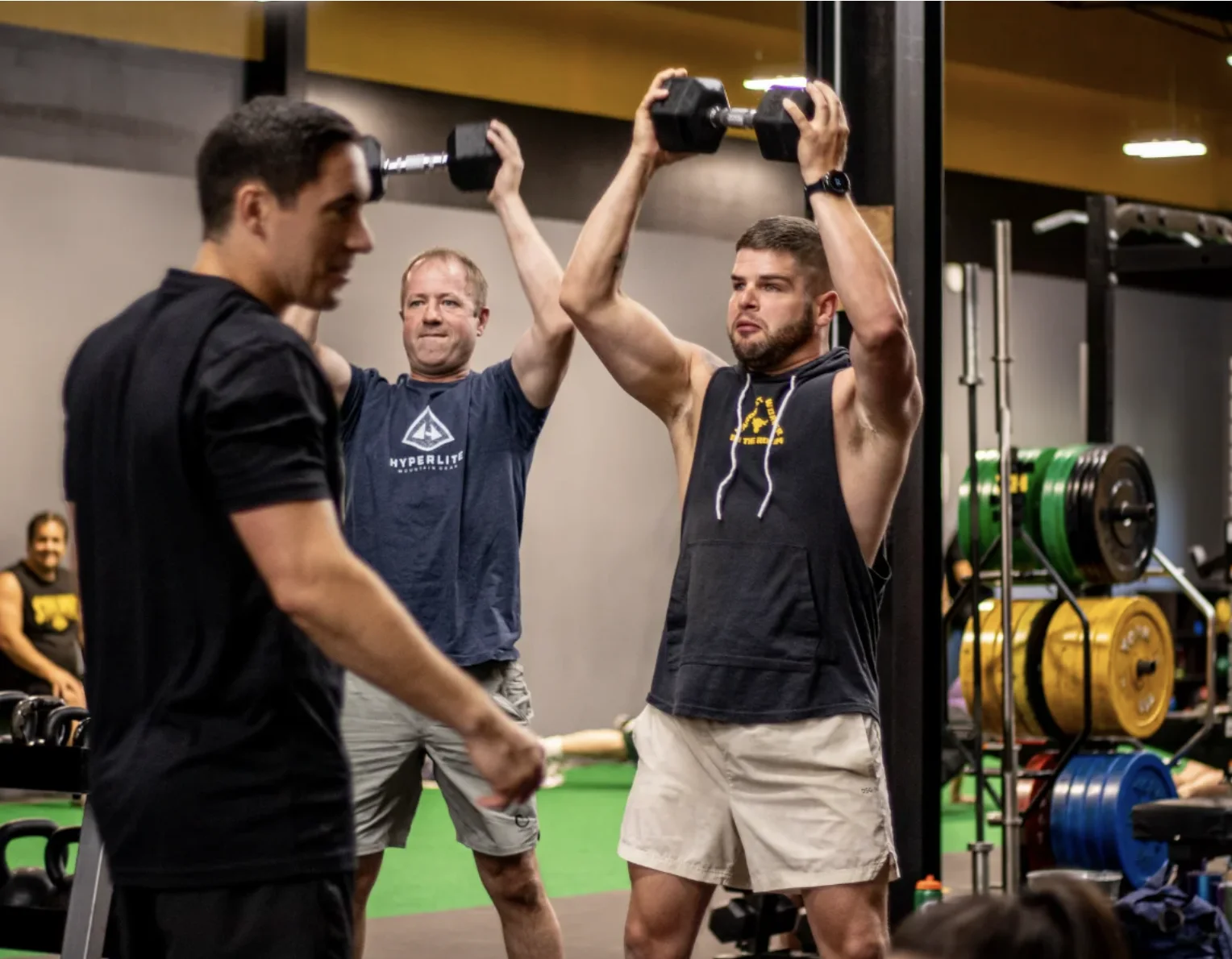Members pressing dumbbells overhead in a Personal Fitness class